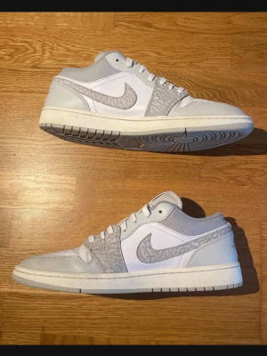 Air jordan 1 low premium elephant print - Snygga Nike Air Jordan 1 Low sneakers i vitt och ljusgrått med ikonisk Swoosh och elefantmönstrade detaljer. Ovandelen är i läder och mesh för en clean look och bra komfort. Klassisk siluett som passar till streetwear och casual outfits.