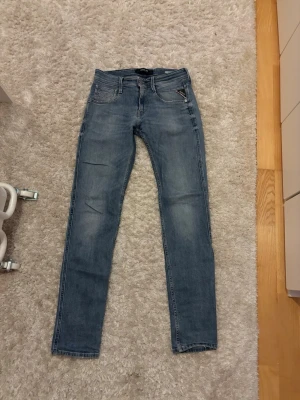 Replay jeans i modell anbass  - Säljer ett par blå slim jeans från Replay med klassisk femficksdesign och dragkedjedetalj på fickan fram. Jeansen har normal midja och är tillverkade i denim med lätt tvättad look. Perfekta för en trendig och avslappnad stil. Pris kan diskuteras.