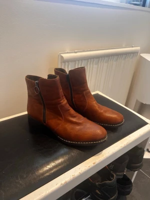 Bruna boots från Rieker med dragkedja - Snygga bruna boots från Rieker i mjukt läder med dekorativ söm längs sulan. Modellen har en låg klack och dragkedja på sidan. Använda 1 gång!