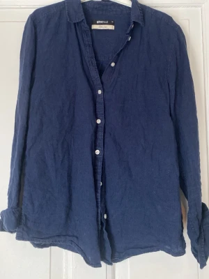 Mörkblå linneskjorta från Gina Tricot - Snygg mörkblå skjorta i 100% linne från Gina Tricot. Skjortan har klassisk krage, knappar framtill och långa ärmar. Perfekt för en avslappnad men stilren look. Passar till både jeans och kjol.