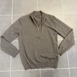 Beige halvzip-tröja från Stenströms - Snygg beige stickad tröja från Stenströms med halvzip och ribbade muddar. Tröjan har en klassisk passform och hög krage som kan bäras både uppvikt och nedvikt. Perfekt för lager på lager och stilrena outfits. Storlek M men sitter mer som S. 