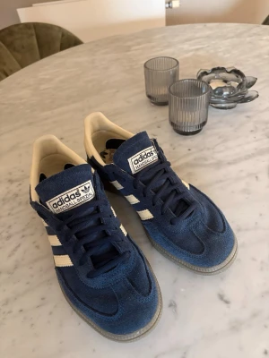 Adidas Handball Spezial blå sneakers - Snygga Adidas Handball Spezial sneakers, blåa med vita detaljer och klassiska tre ränder på sidan. Skorna är väldigt sköna och är mycket sparsamt använda så ser nästan ut som nya⭐️ Perfekt nu till våren och sommaren🌸