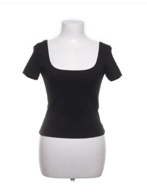 Svart topp med fyrkantig ringning - En stilren svart topp med korta ärmar och fyrkantig ringning. Toppen har en slim passform och är tillverkad i mjukt bomullsmaterial. Perfekt att matcha med jeans eller kjol för en clean look.