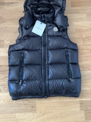Svart dunväst från Moncler - Snygg svart dunväst från Moncler med glansig finish och klassisk logga på bröstet. Den är helt ny inga problem storlek 1=s tar byten och pris kan diskuteras 