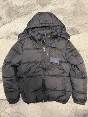 Svart pufferjacka från Polo Ralph Lauren - Säljer en helt ny Ralph Lauren jacka i svart – aldrig använd, kommer med allt 🏷️🔥  • Storlek: M • Skick: 10/10 (helt ny) • Färg: svart – passar till allt • Passform: clean & snygg fit  Perfekt jacka för både vardag och finare outfits. Säljer då den är stor för mig.  📦 Kan skickas direkt ⚡️ Snabb affär prioriteras!