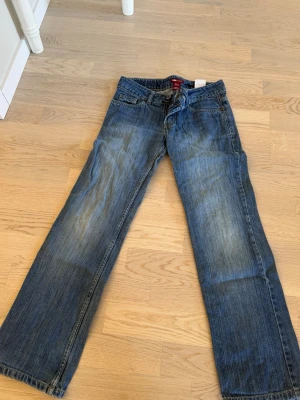 Blå bootcut jeans  - Säljer ett par klassiska blå bootcut jeans De har en snygg tvätt med slitningar, fem fickor och normal midja. Jeansen är i mjuk denim och har en avslappnad passform som ger en chill vibe till din outfit. Passar 152 xxs 