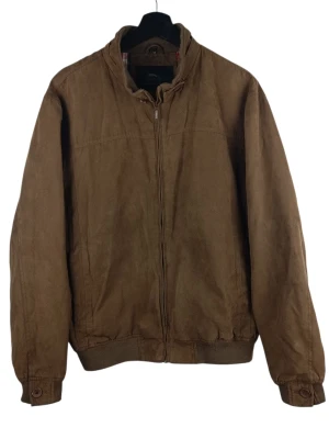 Rappson of Sweden Brun Mockajacka, C50 (M->L) - Jacka från Rappson of Sweden. Jackan har en dragkedja framtill och knappar vid kragen och ärmsluten. Insidan är fodrad med ett rutigt mönster i rött, svart och vitt, samt två innerfickor. Små fläckar på vänster ärm. Armhåla till armhåla: 58cm Axelbredd: 50cm Långt: 69cm Armlängden från armhåla: 47cm