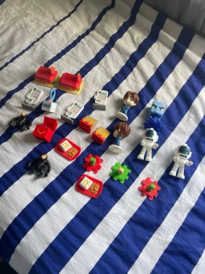 Samling McDonald's leksaker - Säljer en samling McDonald's leksaker i plast, blandat med figurer, brickor, astronauter, apor, pusselbitar och miniatyrmat. Flera färger som röd, vit, blå, grön och svart. Perfekt för dig som gillar samlarprylar eller vill ha roliga småsaker.