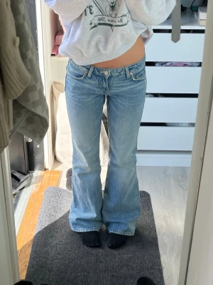 Superlågmidjade Ljusblå bootcut jeans från weekday - Modell: Nova slim bootcut jeans. Storlek : w24 L32.                           Säljer ett par ljusblåa bootcut jeans från weekday med klassisk femficksdesign och låg midja. Jeansen har en snygg tvättad look och är tillverkade i denim med lätt stretch. Perfekta för en avslappnad och trendig stil.