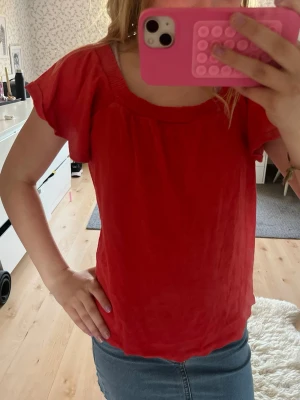 Röd topp med volangärm - Snygg röd topp med rund halsringning och korta volangärmar. Från Lindex storlek 146/152 men passar xs❤️ har ett litet hål på baksidan men inget man tänker på💗