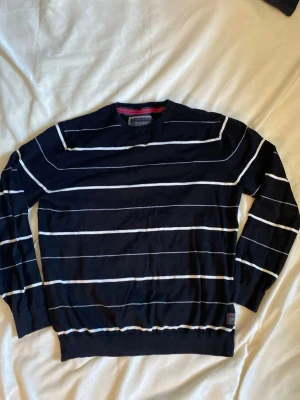 Svart randig tröja från Esprit - Snygg svart tröja från Esprit med tunna vita horisontella ränder. Klassisk rund halsringning och långa ärmar. Perfekt för dig som gillar enkel men stilren design. Materialet känns mjukt och lätt, vilket gör den skön att bära hela dagen.