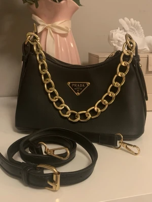 Handväska - Super gullig handväska köpt i spanien, har en guldkedja som handtag men det medkommer en längre axelrem. Skriv om du har frågor, pris kan diskuteras. EJ äkta! 