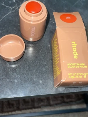 Rhode Pocket Blush Sun Sock - Rhode Pocket Blush i färgen Sun Sock är ett krämrouge i stickformat. Färgen är en varm, solkysst orange ton som ger kinderna en fräsch glow. Förpackningen är kompakt och beige med lock, perfekt att ha med i väskan. Innehåller 5,3g produkt.