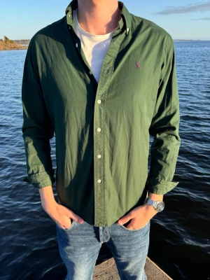 Grön skjorta från Ralph Lauren - Tjena nu har vi fått in denna gröna skjortan från Ralph Lauren med lång ärm och knappar framtill. Skicket på skjortan visas på bilderna och vi skulle bedöma de som 9/10 skick. Storleken är S men passar även M. Vårt pris endast 379kr men kan få ner vid snabb och smidig affär😊 Skjortan har en liten broderad logga på bröstet och är tillverkad i bomull. Perfekt till jeans för en avslappnad men snygg look. // Studio II Resell 💙