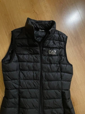Svart dunväst från EA7 Emporio Armani - Armani väst i nyskick säljes då den ej används. storlek xs. pris kan diskuteras vid seriöst intresse.
