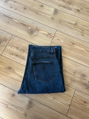 Blå raka jeans från Abrand jeans - Säljer ett par blå/grå raka jeans från Abrand jeans  med hög midja och klassisk femficksdesign. Jeansen har en mörk tvätt och en liten logga på bakfickan. Perfekta för en avslappnad och trendig look. 