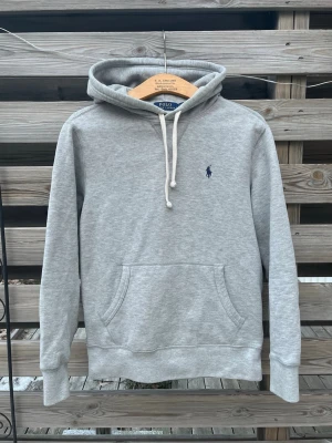 Grå Ralph Lauren Hoodie  - Mycket snygg Grå Ralph Lauren Hoodie. Storlek S, kan även passa en större XS. Mycket fint skick, nästan nyskick. Enbart använd ett fåtal gånger. Hör gärna av er vid funderingar🙌 