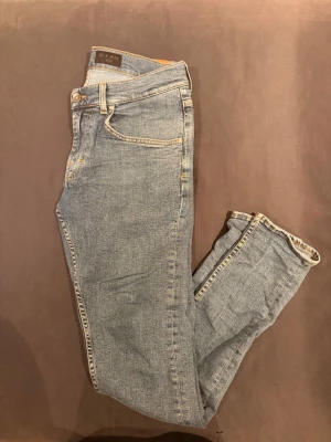 Blå Tiger of Sweden jeans - Säljer ett par klassiska blå jeans från Tiger of Sweden. Modellen har smal passform, fem fickor och guldfärgade sömmar. Jeansen är tillverkade i denim och har en tidlös look som passar till det mesta. Perfekta för dig som gillar stilrena och bekväma jeans.