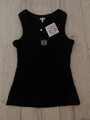 Svart ribbad linnetopp från Loewe - Snygg svart ribbad linnetopp från Loewe med broderad vit logga framtill. 