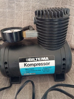 Biltema kompressor 12V - Kompakt svart kompressor från Biltema, modell 15-598, med tryckmätare och anslutningsslang. Drivs med 12V och har maxtryck på 14 kg/cm². Perfekt för att pumpa däck eller andra uppblåsbara saker. Tillverkad i metall och plast.