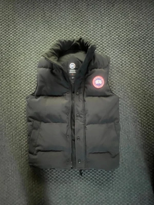 Canada goose Garson vest - Västen är 110% äkta och nypris just nu ligger på 6500:- ja köpte den av min kusin som då köpte den på Nk år 2021 har ja för mig (ja har foto på kvittot) västen är nästan toppskick men bara lite smutsig men går bort när man tvättar alltså inte permanent smuts! Model är (canada goose 4151M) och är i färgen navey marine. Den är både varm och luftig då den håller värmen på kallare dagar och lite svalnare på varmare dagar! Om ni har frågor och funderingar är de bara att Sicka!