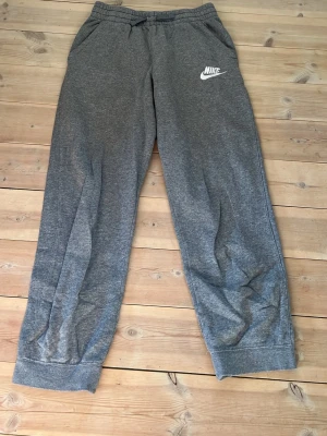 Gråa mjukisbyxor från Nike - Säljer dessa mjukisbyxor från Nike💕Dem är i väldigt bra skick då dem knappt är använda. Dem är i storlek 158-170. 