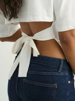 Vit croppad topp med knytband - Säljer en vit croppad topp med knytband i midjan. Toppen har rund halsringning och halvlånga ärmar. Perfekt för dig som gillar en enkel men trendig look. Materialet känns som bomull och toppen är lätt att styla till olika outfits.