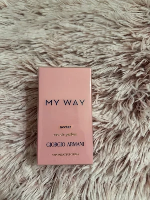 Giorgio Armani My Way Nectar EdP 50ml - Upptäck My Way Nectar Eau de Parfum från Giorgio Armani. Parfymen kommer i en stilren, ljusrosa rektangulär kartong med elegant text. Doften är en modern och fräsch tolkning av blommiga toner, perfekt för dig som gillar exklusiva och trendiga parfymer.