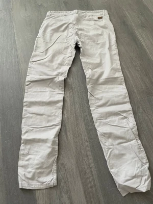 Beiga chinos från U.S. Polo Assn. - Snygga beiga chinos från U.S Polo Assn med slim fit/ straight ben och klassisk passform. Byxorna har bälteshällor, två bakfickor och är tillverkade i ett mjukt bomullsmaterial. Perfekta för en clean och stilren look.