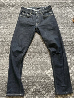 Mörkblå jeans från Replay - Säljer ett par mörkblå jeans från Replay, modell Grover. Klassisk femficksdesign med raka ben och kontrastsömmar. Jeansen har en stilren look och är tillverkade i ett slitstarkt denimtyg. Perfekta för dig som gillar en enkel men snygg stil. Passar dig som är mellan 170-185 skulle jag säga! 