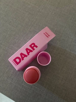 DAAR Cosmetics Coral Crush Rouge - Krämrouge från DAAR Cosmetics i färgen Coral Crush. Kommer i en smidig stickform med rosa hylsa och matchande förpackning. Färgen är en fräsch korallton som ger kinderna ett naturligt glow. Perfekt att ha i väskan för snabba touch-ups.  Använd bara 1 gång. 