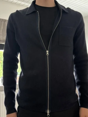 samsøe samsøe full zip  - Snygg mörkblå ziptröja med krage och bröstficka från samsøe samsøe. Tröjan har en rak passform, långa ärmar och dragkedja framtill. Materialet är mjukt och lite tjockare, perfekt för lager på lager. Enkel och stilren design som passar till det mesta.