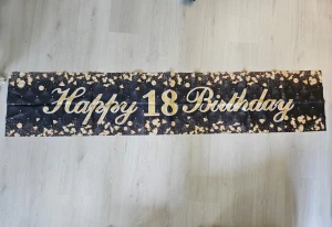 Happy 18 Birthday banderoll svart/guld - Snygg banderoll med texten 'Happy 18 Birthday' i guld på svart bakgrund med guldfärgade konfettimönster. Perfekt till 18-årsfesten för att skapa festlig stämning. Tillverkad i tyg eller plastmaterial. 200 x 40 cm