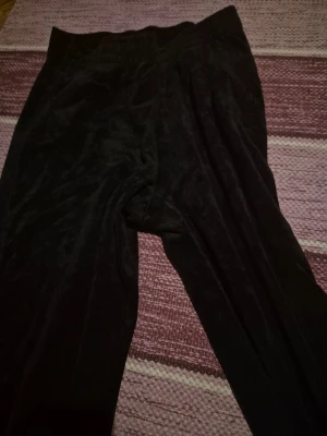 Svarta mjuka velourbyxor - Säljer ett par svarta byxor i mjuk velour med resår i midjan. Perfekta för chill dagar hemma när du vill ha något riktigt bekvämt. Byxorna har en avslappnad passform och är supermysiga att ha på sig.