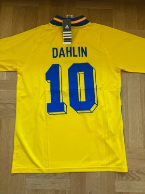 Dahlin #10 – Sverige Hemma 1994 (storlek M) - Dahlin #10-tryck. Sverige Hemma 1994 (gul). Storlek M. Helt ny och aldrig använd. Skickas snabbt 🚚💨  Mått (M): Halvt bröstmått 53 cm • Längd 74 cm • Ärmbredd 23 cm • Axelbredd 44 cm • Ärmlängd 40 cm • Manschett 19 cm.  🔥 Fan Edition – normal passform. 🇸🇪 Sverige landslag.  📩 Frågor eller prisförslag? Skicka gärna ett meddelande! 🛍 Bundle-rabatt upp till 20% 💰 📦 Skickas samma eller nästa dag 🌟