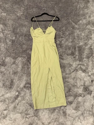 Ljusgrön klänning med snörning från Zara - Trendig ljusgrön  med smala axelband och snygg snörningsdetalj i ryggen. Klänningen har en v-ringad front och en slits framtill för extra stilpoäng. Perfekt för sommarens alla tillfällen!