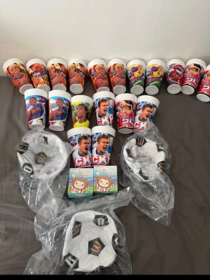 McDonald's samlarmuggar och fotbollsskålar - 5 för 150kr Samling med McDonald's samlarmuggar med motiv från olika sporter och kända profiler, samt tre vita fotbollsskålar med svart mönster och McDonald's-logga. Två små barnböcker medföljer också. Perfekt för dig som gillar unika McDonald's-prylar.