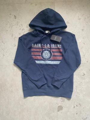 Saint Laurent hoodie  - Hej! Nu säljer jag denna riktigt snygga och stilrena Saint Laurent-hoodie. Den är helt ny och i storlek S.  Tveka inte att höra av dig om du har några frågor eller funderingar.  Priset är inte hugget i sten.  Mvh, Agge