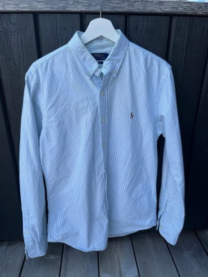 Grön randig skjorta från Polo Ralph Lauren - Klassisk grön och vitrandig skjorta ifrån Ralph Lauren. Bara haft på mig ett fåtal gånger du jag snabbt växte ur den. Bara att höra av sig angående frågor eller pris.