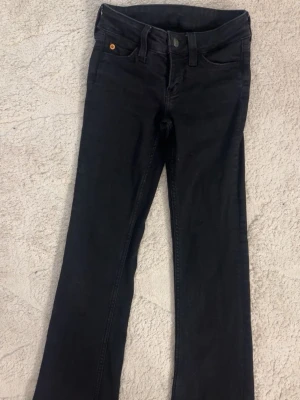 Svarta Cheap Monday jeans bootcut - Snygga svarta jeans från Cheap Monday med bootcut-modell i storlek 24/30. Har tagit bort den stora lappen som sitter där bak