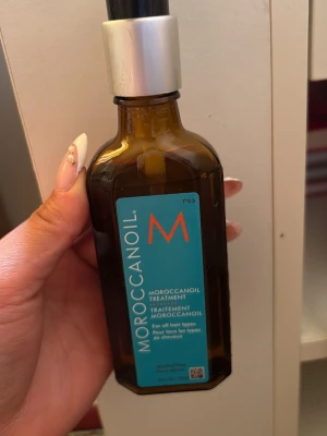 Moroccanoil Treatment hårolja - Moroccanoil Treatment är en ikonisk hårolja i en brun glasflaska med blå etikett och pump. Oljan passar alla hårtyper och ger glans, näring och mjukhet. Perfekt för att tämja friss och ge håret en silkeslen känsla.