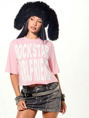 Rosa croppad t-shirt med tryck - Ljusrosa  croppad t-shirt med stort vitt tryck 'ROCKSTAR GIRLFRIEND' framtill. T-shirten har korta ärmar och en loose passform, perfekt för en avslappnad eller y2k stil. Helt oanvänd!🥰
