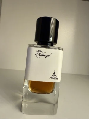 Paris Corner Rifaaqat Eau de Parfum - Rifaaqat Eau de Parfum i en stilren, rektangulär glasflaska med svart plastlock. Doften har kryddiga och varma noter med inslag av elemi, rosa och svartpeppar, saffran, olibanum, vanilj och cederträ. 85ml flaska, avgör mängden som är kvar från bilderna. PRIS KAN DISKUTERAS , mvh