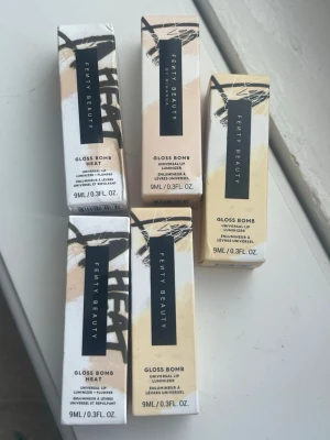 Fenty Beauty Gloss Bomb läppglans - Säljer fem olika Fenty Beauty Gloss Bomb läppglans i nyanserna Hot Chocolit, Riri, Fussy Heat och Hot Cherry. Läppglansen kommer i snygga förpackningar och ger glansiga, fylliga läppar. Varje tub innehåller 9 ml och har en mjuk applikator.