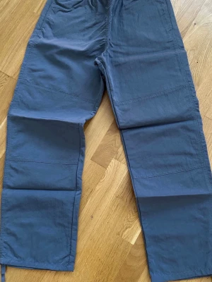 Gråa mjukisbyxor från Samsøe Samsøe - Snygga grå mjukisbyxor från Samsøe Samsøe med avslappnad passform och resår i midjan. Tillverkade i ett mjukt och bekvämt material, perfekta för chill dagar. Byxorna har raka ben och diskreta sömdetaljer över knäna.
