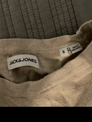 Beige stickad tröja Jack & Jones - Beige stickad tröja från Jack & Jones med rund halsringning och långa ärmar. Tröjan har ribbade muddar vid ärmslut och nederkant, vilket ger en snygg och enkel look. Perfekt att matcha med jeans eller chinos.