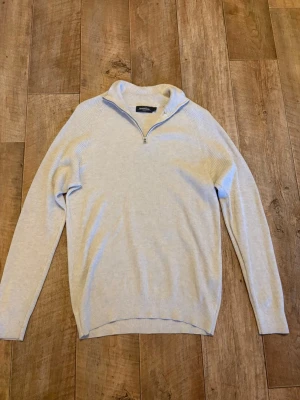 Ljusbeige ribbad halvzip-tröja - Snygg ljusbeige ribbad tröja från Dressman med halvzip och hög krage. Tröjan har långa ärmar och är tillverkad i ett mjukt, tunt material som passar perfekt för lager på lager. Enkel och stilren design som funkar till det mesta.