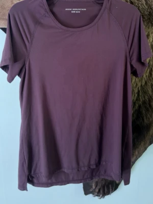 Lila tränings-tshirt High Mountain - Säljer en lila tränings-tshirt från High Mountain i damstorlek 38/40. T-shirten har rund halsringning, korta ärmar och är tillverkad i ett mjukt och stretchigt funktionsmaterial som passar perfekt till träning eller sportaktiviteter.