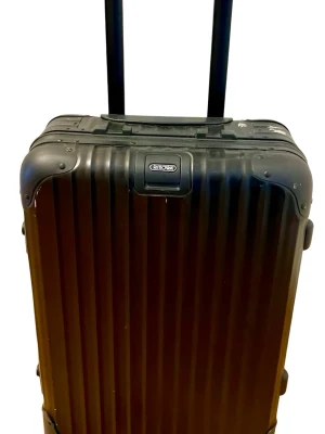 RIMOWA ”Topas Stealth” 32L - RIMOWA ”Topas Stelth” 32L i svart aluminium. Denna version med 2 hjul i silikon med kullager har utgått ur deras sortiment och blivit ersatt med en version 4 mindre hjul i plast. Med denna kan du enkelt dra väskan på t ex kullersten. Väskan är i gott använd skick utan några bucklor och har alltid rest som incheckat bagage. Jämför gärna priset med liknande väskor som ligger ute på internationella plattformar som Ebay  etc.  