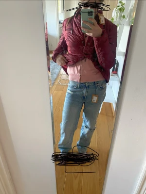 Ljusblå low waist jeans - Säljer ett par ljusblå  jeans med lite baggy och slitningar, inklusive ett stort hål på ena knät för en trendig, avslappnad look. Klassisk femficksmodell med knappgylf och etikett i midjan. Perfekta för dig som gillar streetstyle.